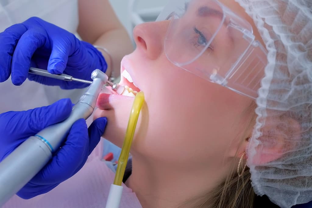 A dentist performs a dental procedure on a patient wearing protective eyewear.